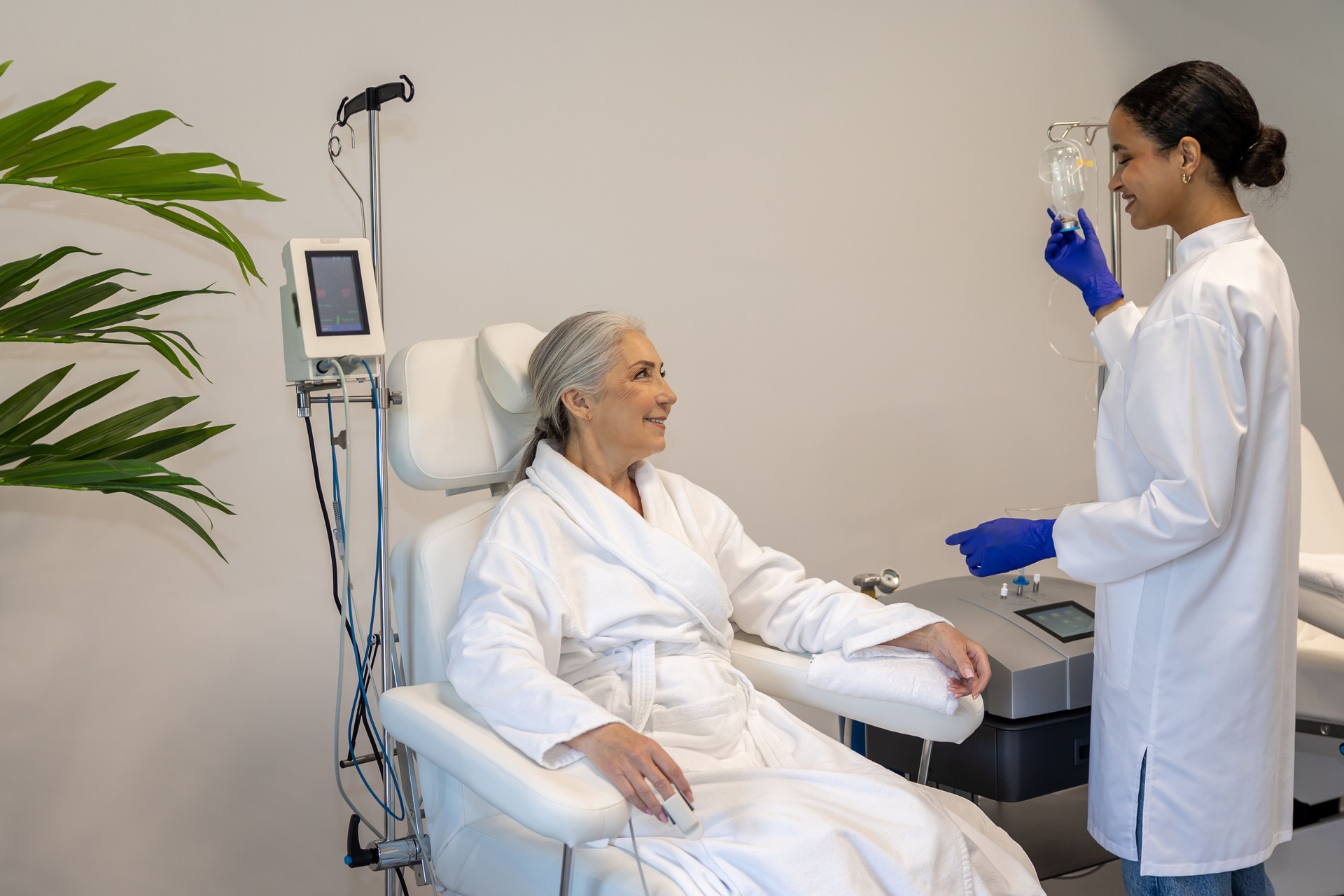 Doctor doing IV infusion for senior woman patient in beauty clinic.