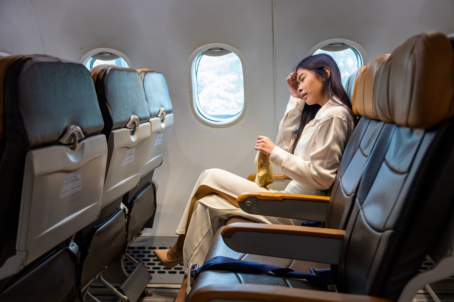 Asian woman is feeling dizzy and holding to vomit bag during the flight in the airplane due to the motion and travel sickness that cause dizzy for aerophobia and transportation